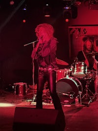 a woman on stage with a microphone and drums