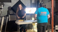 two people standing in front of a table in a recording studio