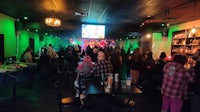 a crowd of people in a room with green lights